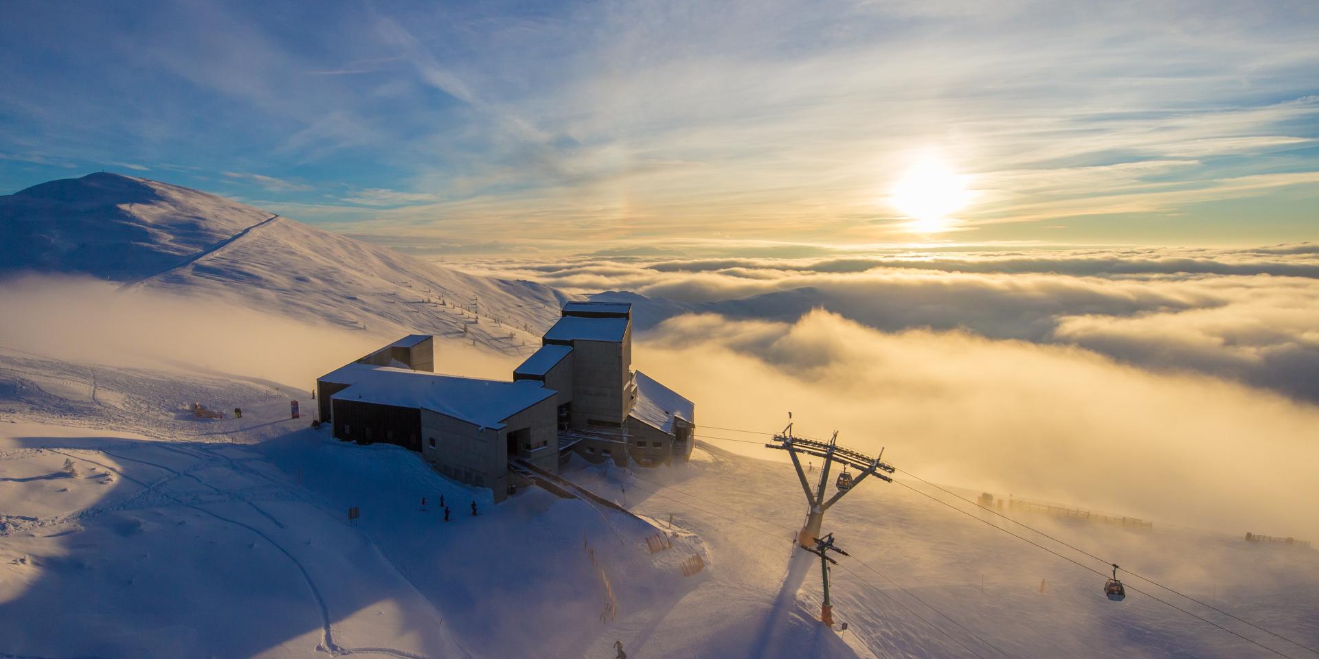 bad_kleinkirchheim_skigenuss-original_(f)_Gert-Steinthaler_(c)_Kaernten-Werbung Ein Foto vom Gipfel der Berge auf der Skistation und der Himmel bedeckt mit Wolken und Sonnenschein, perfekt für einen Winterurlaub in Kärnten